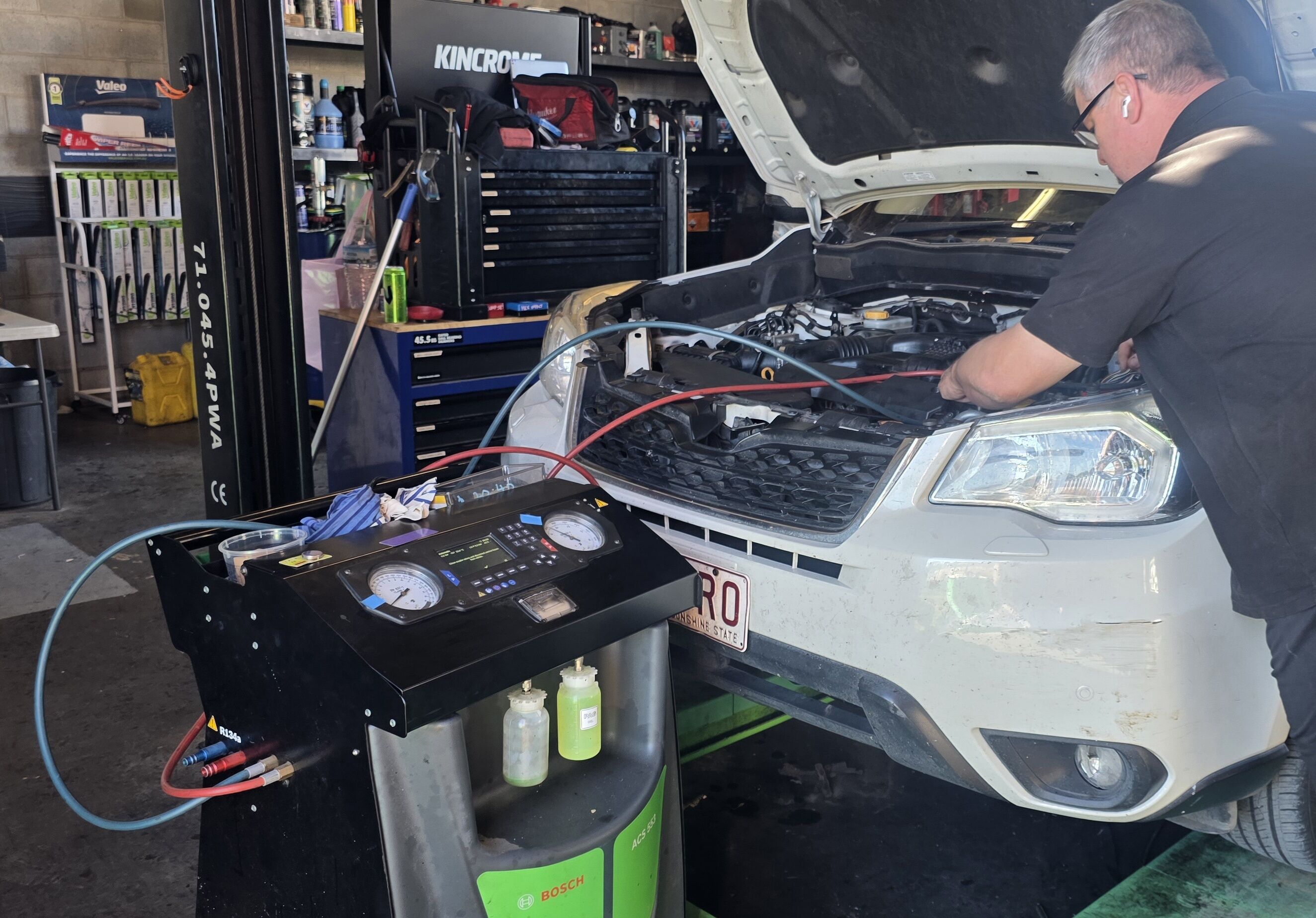 AC technician at our Calliope workshop Technician servicing vehicle air conditioning with a Bosch ACS 553 at Total Mobile Mechanical Services Calliope